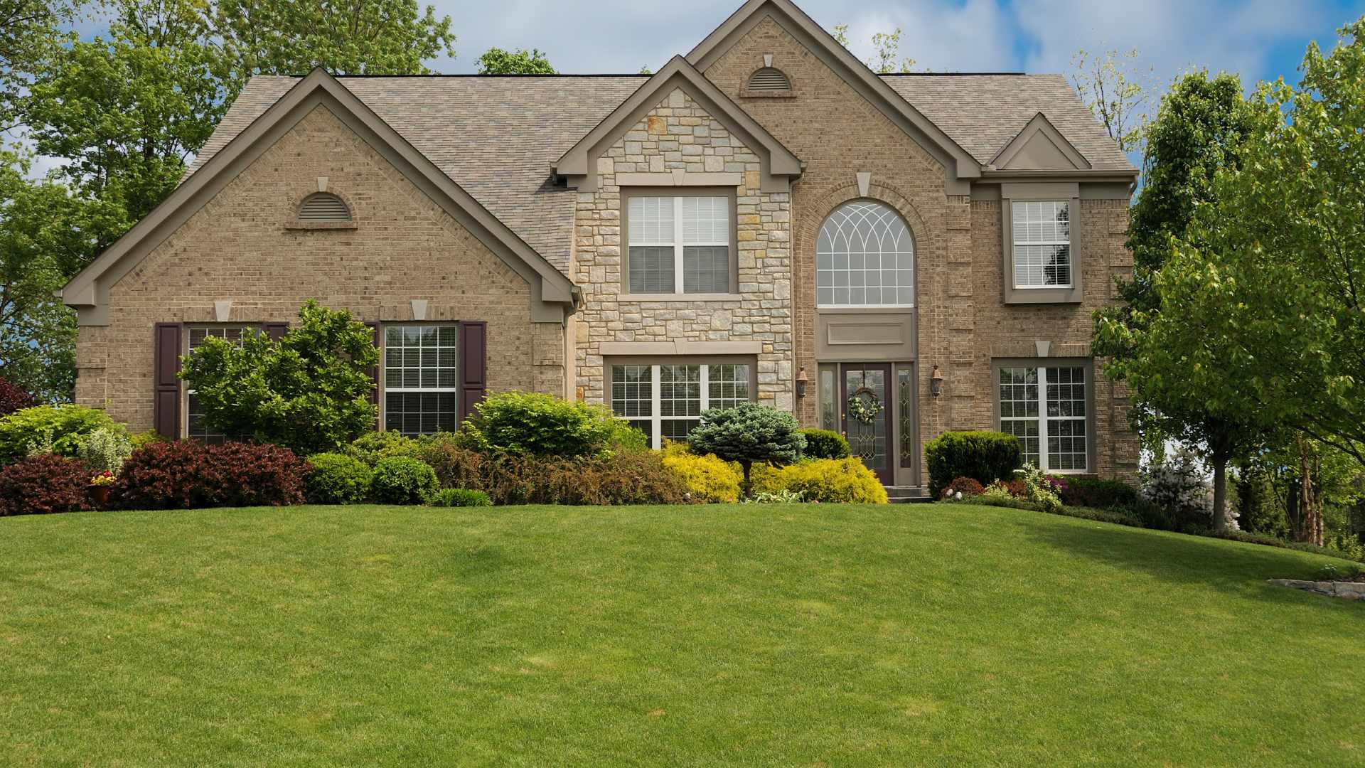Large home with a maintained lawn and landscape bed in New Palestine, IN.