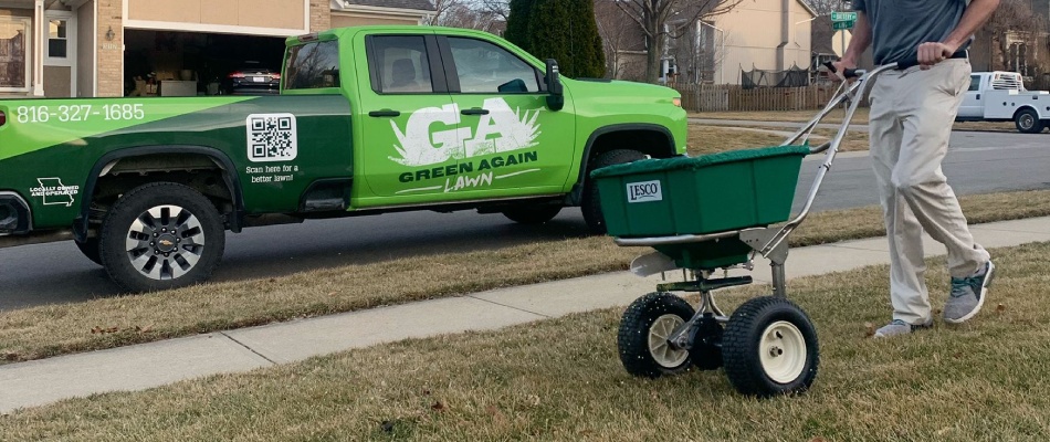 Professional spreading seeds over lawn in spreader in Raymore, MO.