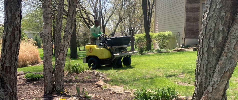 Professional on riding spreader applying seeds to lawn in Kansas City, KS.