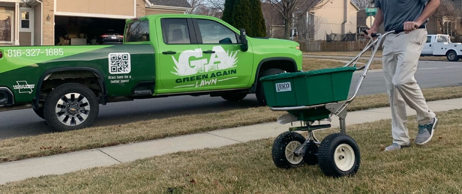 Worker with fertilizer spreader in lawn in Olathe, KS.